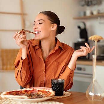 Woman enjoying slice of pizza at home