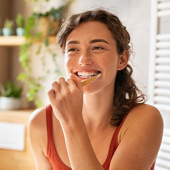Woman smiling while brushing her teeth