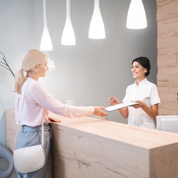 Patient handing dental receptionist clipboard