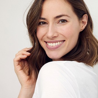 Woman in white shirt looking over shoulder smiling