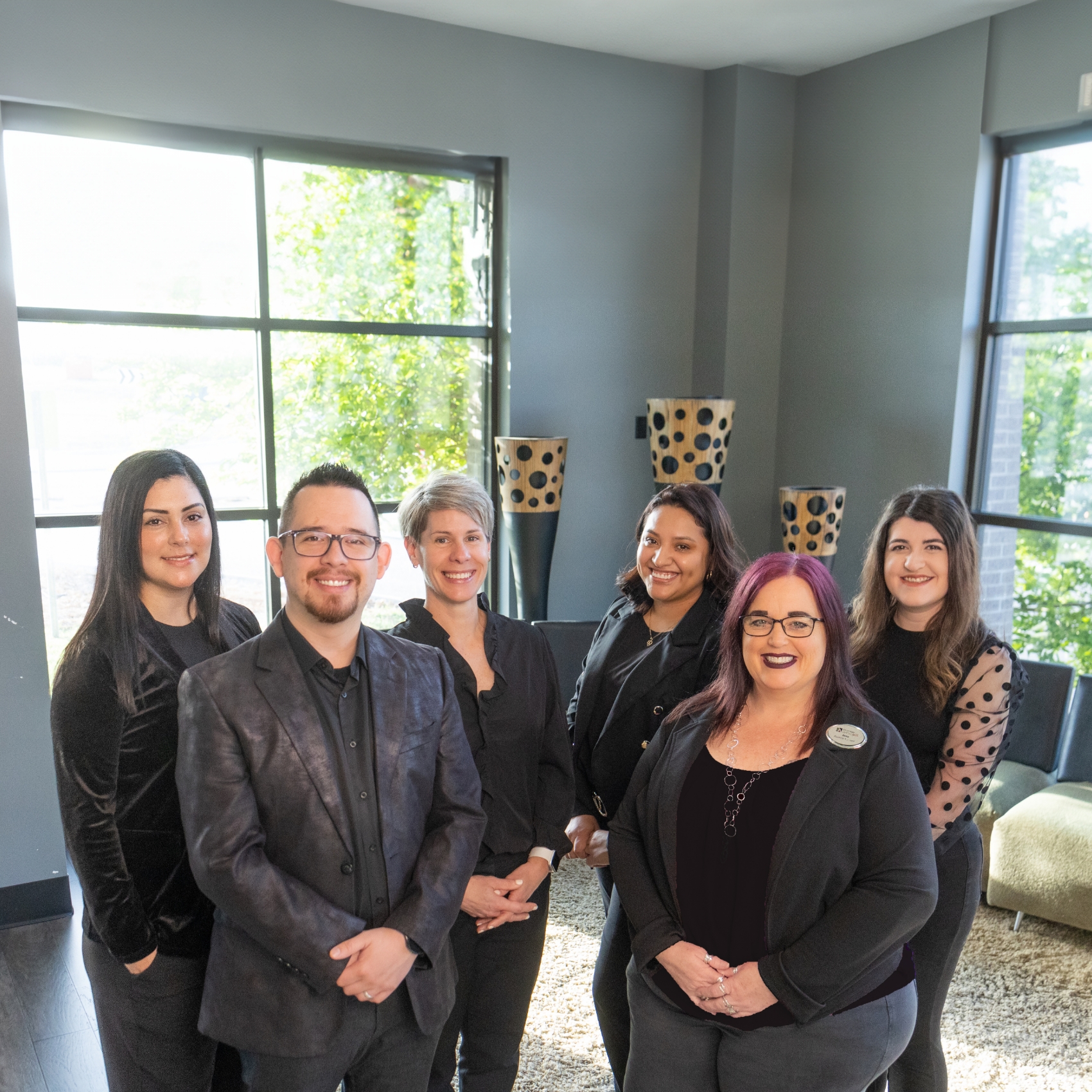 Dental team standing in Rogers dental office and smiling