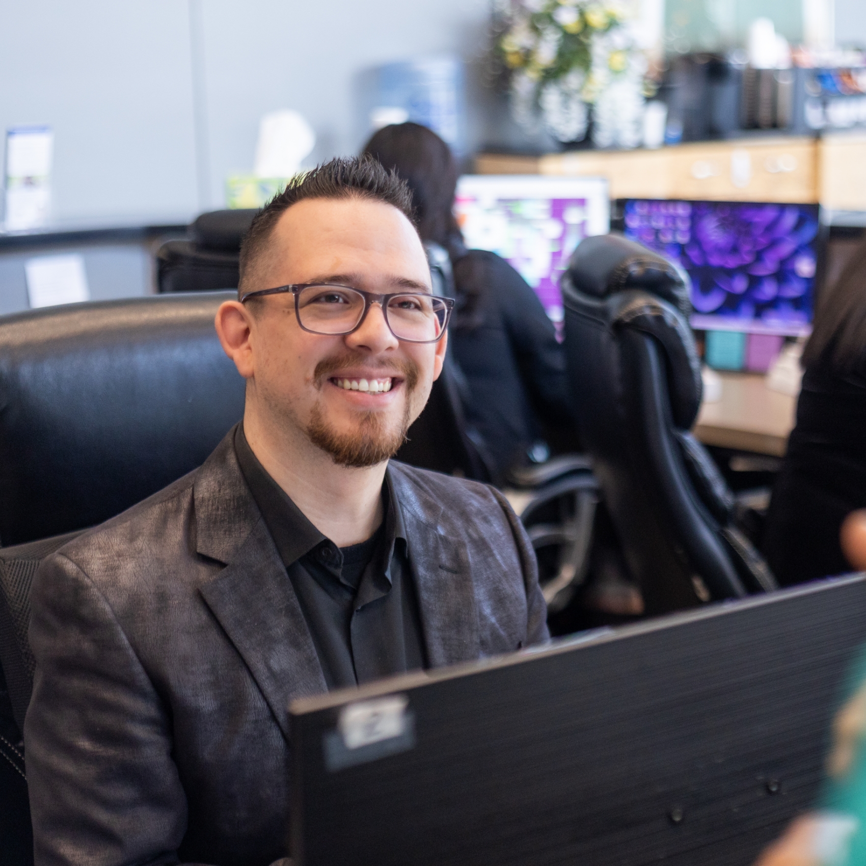 Man sitting in front of computer monitor and smiling