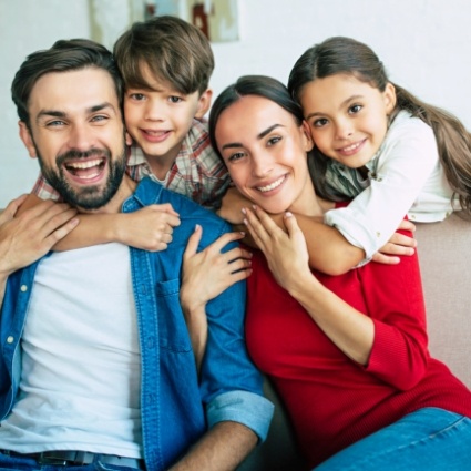 Man and woman on couch being hugged by kids from behind