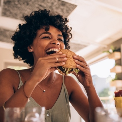 Woman smiling and about to eat a burger