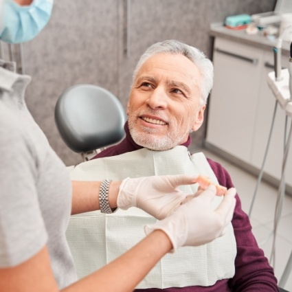 Senior man looking up at dentist and smiling