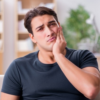 Man in dark blue shirt rubbing jaw