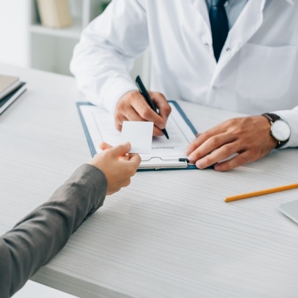 Patient holding dentist card while they write on clipboard