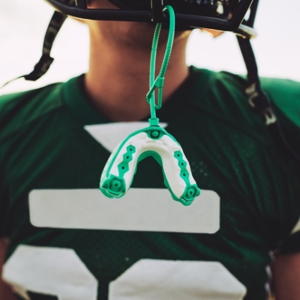 Football player with mouthguard dangling off helmet